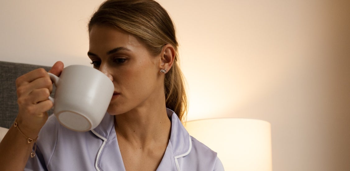 woman sipping mug in bedroom