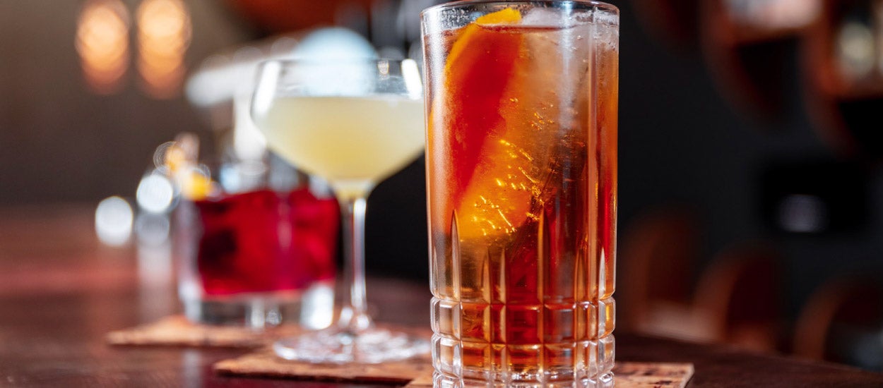 Clear glasses of alcohol on a bar top.