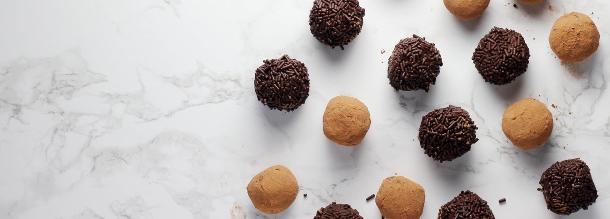 Boost chocolate protein balls recipe. White and dark chocolate protein balls evenly spaced on a white bench top.