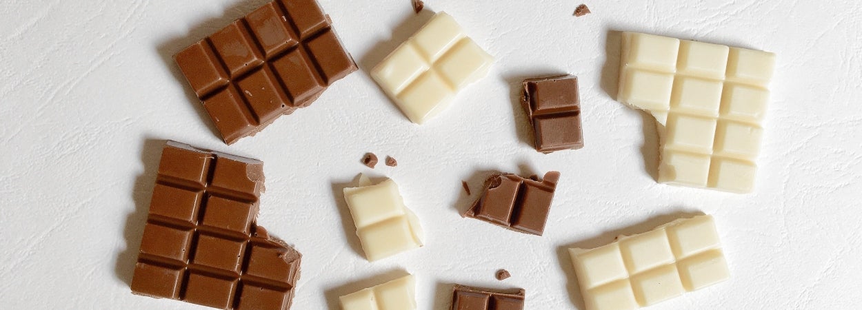 White chocolate protein balls boost recipe. Milk and white chocolate squares evenly spaced on a white bench top.