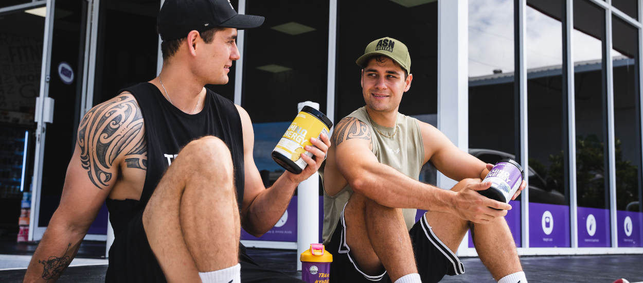 two guys holding amino energy tubs 