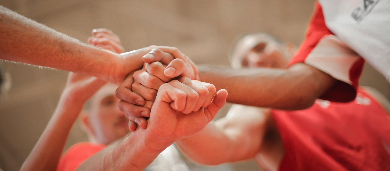 a group of men standing together all putting their fists in one on top of another